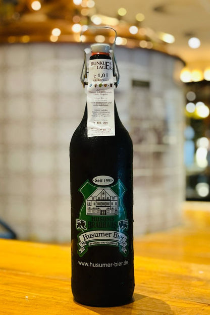 Das Bild zeigt die 1 L Ploppflasche mit Brauhaus Logo gefüllt mit Dunklem Lager.