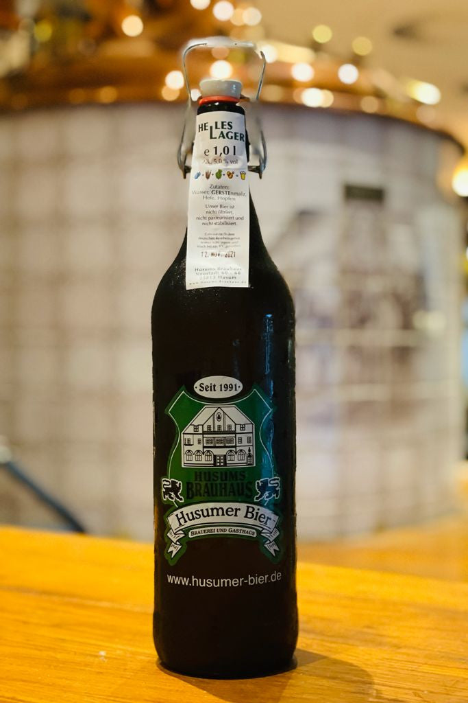 Das Bild zeigt die 1 L Ploppflasche mit Brauhaus Logo gefüllt mit Hellem Lager.