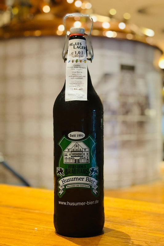 Das Bild zeigt die 1 L Ploppflasche mit Brauhaus Logo gefüllt mit Hellem Lager.