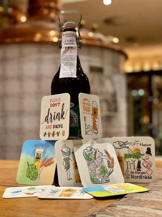 Bild zeigt ein Foto von der 1 L Husums Brauhaus Bierflasche, davor drapiert sind die Bierdeckel. 